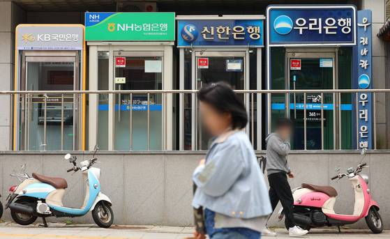 Pedestrians pass by ATM machines for Korea's major banks in Seoul on May 5. [YONHAP]