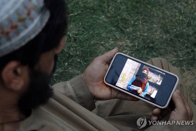 얼굴을 가린 여성 앵커의 뉴스 진행 장면을 보는 아프간 남성 EPA 연합뉴스