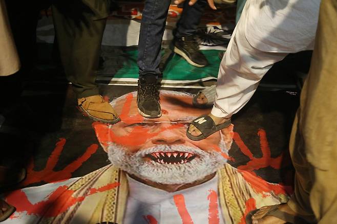 7일 (현지시간) 파키스탄 하이베라바드에서 열린 인도 반대 시위에서 시위대가 나렌드라 모디 인도 총리 사진이 담긴 현수막 위에 서 있다. [AFP]