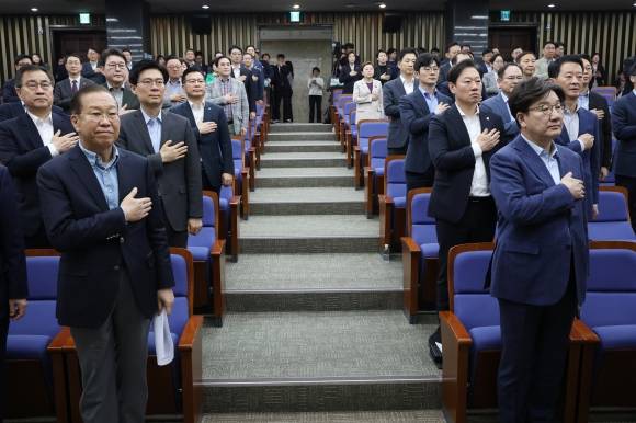 국민의힘 권영세(앞줄 왼쪽) 비상대책위원장과 권성동(앞줄 오른쪽) 원내대표를 비롯한 의원들이 6일 국회에서 열린 의원총회에서 국기에 대한 경례를 하고 있다. 뉴스1