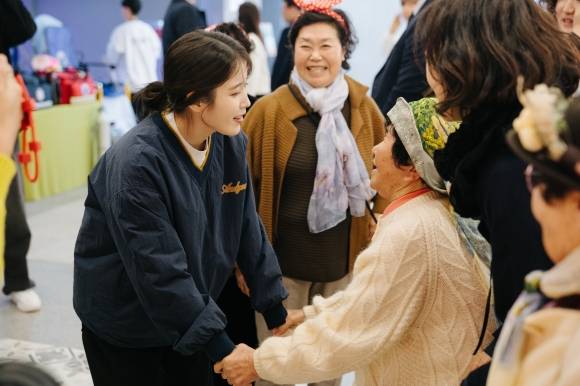 ‘폭싹 속았수다’ 드라마에서 애순역을 맡아 열연한 아이유(왼쪽)가 선흘할망들의 서울 전시회를 찾아 할머니들과 인사를 나누고 있다. 소셜뮤지엄 제공