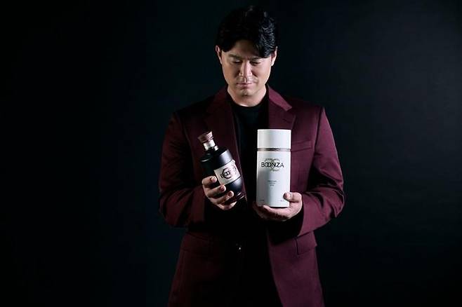 Rapper Choiza holds his bokbunja wine, Boonza, along with its packaging. [BOONZA]