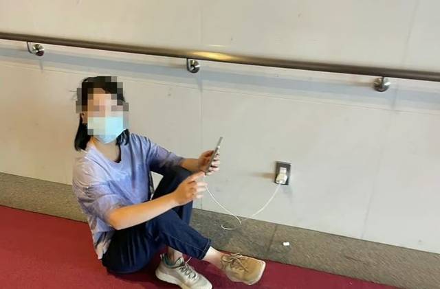 중국인으로 추정되는 한 여성이 공공장소 콘센트를 이용해 휴대전화를 충전하는 모습. SCMP 홈페이지 캡처