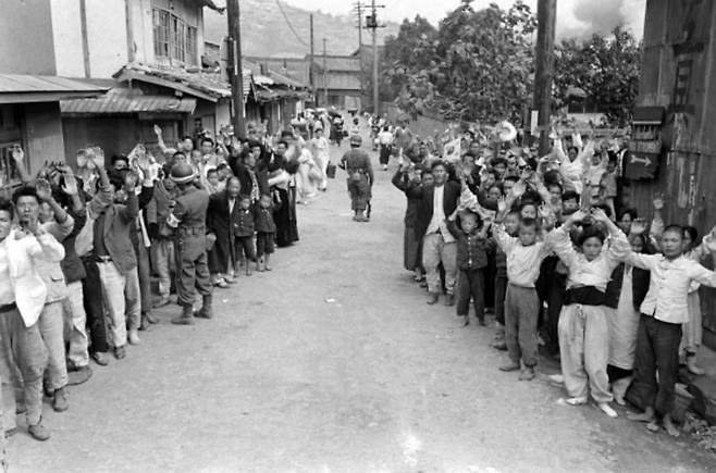 군인들이 협력자를 색출하는 동안 머리 위로 손을 들고 있는 주민과 어린이들 /지영사