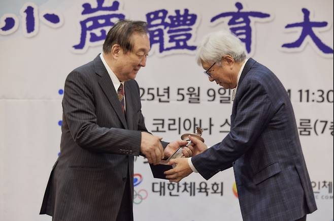 정대철 소강민관식육영재단 이사장(왼쪽)으로부터 대상 트로피를 받고 있는 이인정 회장. 대한산악연맹 제공