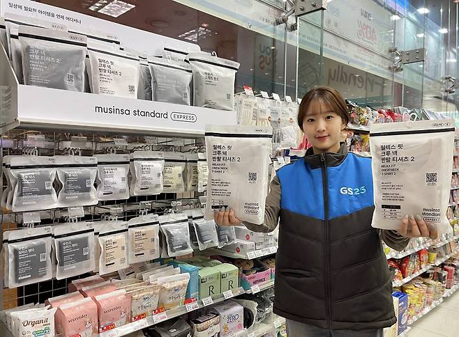 GS25 직원이 GS25 전용 무신사 의류 ‘무신사 스탠다드 익스프레스’ 제품을 들고 있다. [GS25 제공]