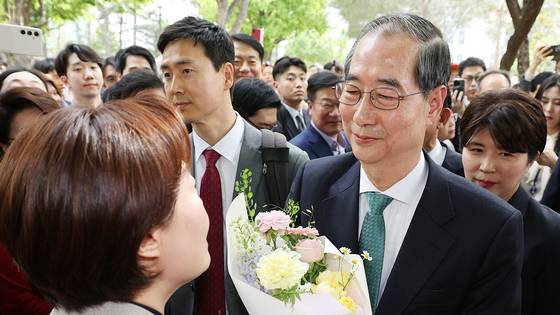 한덕수 무소속 대선 예비후보가 8일 김문수 국민의힘 대통령 후보와의 단일화 회동을 위해 서울 여의도 국회 강변서재로 향하다 꽃다발을 받고 있다. 뉴스1