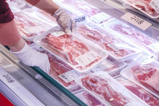 An employee arranges pork belly at a large supermarket in Seoul on April 13. [NEWS1]
