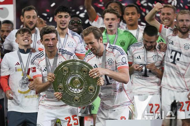 [뮌헨=AP/뉴시스] 독일 프로축구 분데스리가 우승 트로피를 잡고 있는 토마스 뮐러(왼쪽), 해리 케인. 2025. 5. 10.