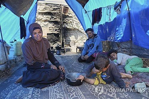 음식을 구하지 못해 좌절한 가자지구의 부모들 (가자지구 칸유니스 AP=연합뉴스) 2025년 5월 9일 가족이 먹을 음식을 구하기 위해 가자지구 남부 칸유니스의 한 급식소에 갔으나 빈손으로 돌아온 주부 와르드 나르(왼쪽)가 천막에서 AP통신 사진기자와 얘기하고 있는 가운데 남편 모하메드 자하르나(가운데 위)와 아들 라에드(가운데 아래), 딸 샐리(오른쪽)가 지켜보고 있다. (AP Photo/Abdel Kareem Hana) 2025.5.10.