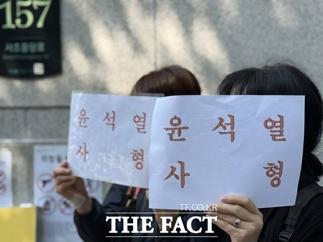 내란 우두머리 혐의로 기소된 윤석열 전 대통령의 세 번째 재판이 열린 12일 서울중앙지법 동문 앞에서 여성 2명이 '윤석열 사형' 손팻말을 들고 있다. /정인지 기자