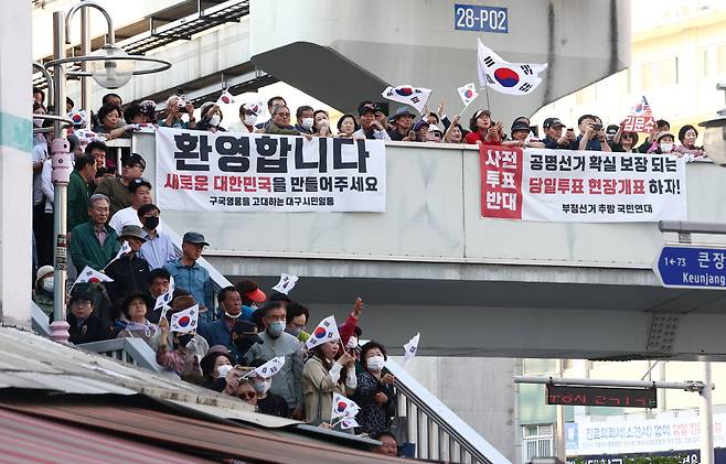 제21대 대통령 선거 공식 선거운동 첫날인 12일 김문수 국민의힘 대통령 후보가 대구 중구 서문시장에서 유세를 하고 있는 가운데 시민들이 태극기를 들고 응원하고 있다. /뉴스1