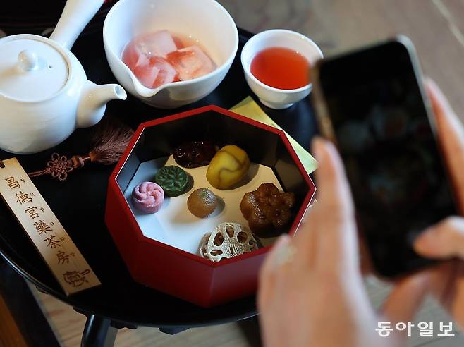 12일 서울 종로구 창덕궁 약방에서 열린 2025년 창덕궁 약다방 사전 행사에서 한 외국인이 전통다과를 스마트폰 카메라로 촬영하고 있다.  송은석 기자 silverstone@donga.com