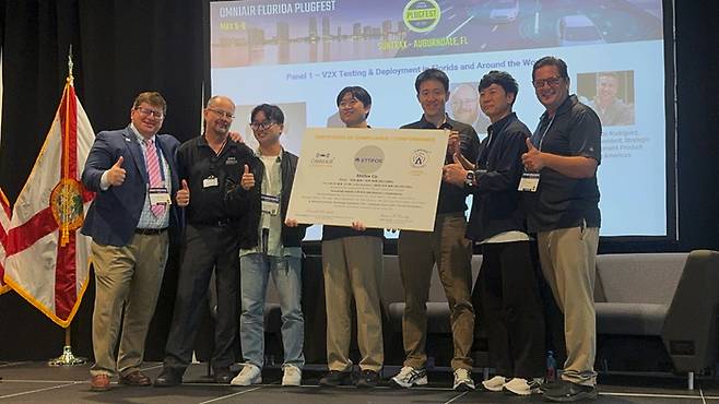 지난 9일 미국 플로리다 선트랙스에서 열린 옴니에어 플러그페스트 현장에서 인증서 수여식 이후 회사 관계자들이 기념사진을 촬영하고 있다. (사진=에티포스)