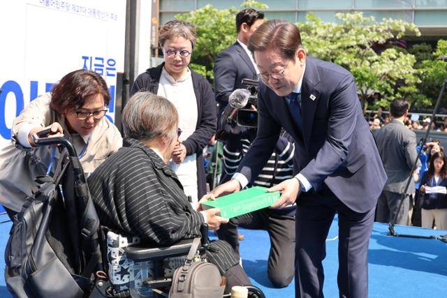 이재명 더불어민주당 대통령 후보가 12일 서울 중구 청계광장에서 빛의 혁명 광화문 유세 시작을 알리며 모두의 질문Q 녹서를 전달 받고 있다. 뉴스1