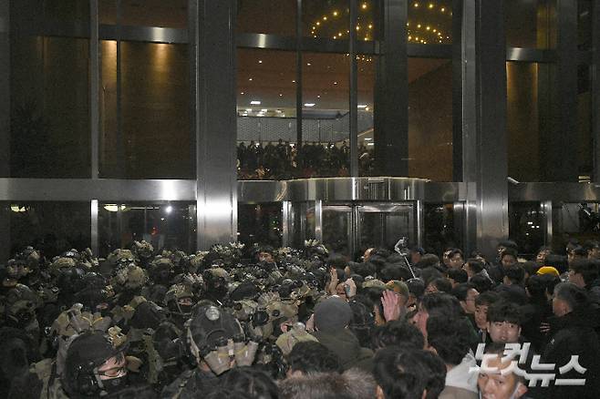 지난해 12월 3일 밤 윤석열 전 대통령이 비상계엄을 선포한 가운데 서울 여의도 국회에서 경내로 진입하려는 계엄군과 저지하려는 시민 및 국회 관계자들이 대치하고 있다. 박종민 기자