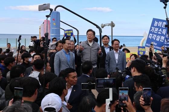 이재명 더불어민주당 대선 후보가 지난 3일 강원도 삼척의 삼척해수욕장을 찾아 지지를 호소하는 가운데 지지자 중 일부가 '농어촌기본소득 즉각실현'이라고 적힌 손팻말을 들어 보이고 있다. 연합뉴스