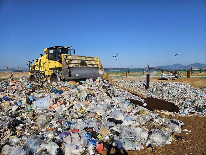 [인천=뉴시스] 오정우 기자 = 지난해 6월 28일 수도권매립지 제3-1매립장 갈색 토양 위로 가죽 신발과 옷가지, 과자, 미처 걸러지지 않은 플라스틱 물병 등이 널브러졌다. 갈매기와 까마귀 약 60마리가 흰색, 파란색, 보라색의 다양한 지역에서 온 종량제 봉투를 뜯고는 닭 뼈를 쪼아댔다. 2024.06.05. friend@newsis.com *재판매 및 DB 금지