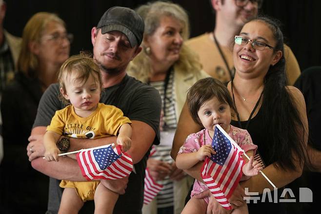 [덜레스=AP/뉴시스] 미국 국기를 든 남아프리카공화국계 아프리카너들이 12일(현지 시간)   미 버지니아주 덜레스에 있는 덜레스 국제공항에 도착하고 있다. 이날 아프리카너(16세기 이후 네덜란드 등 유럽에서 남아공으로 이주해 정착한 백인) 59명이 난민 자격으로 미국에 입국했다. 취임 뒤 사실상 난민 수용을 중단한 도널드 트럼프 행정부가 남아공 백인의 난민 지위를 인정해 미국 내 정착을 허용해 논란이 일고 있다. 2025.05.13.