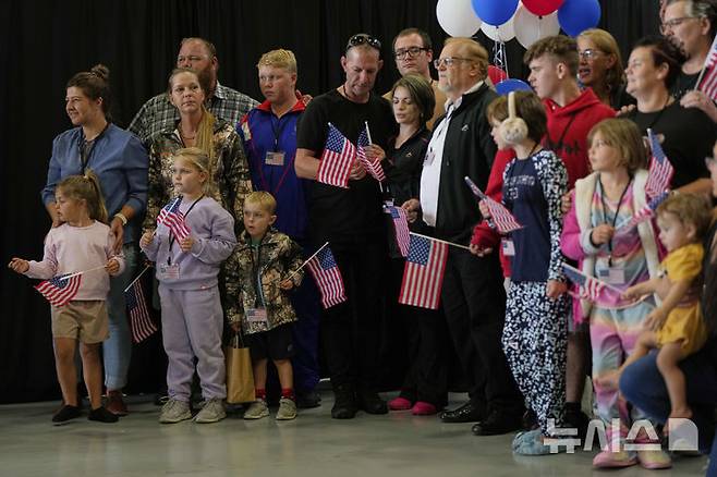 [덜레스=AP/뉴시스] 미국 국기를 든 남아프리카공화국계 아프리카너들이 12일(현지 시간) 미 버지니아주 덜레스에 있는 덜레스 국제공항에 도착하고 있다. 이날 아프리카너(16세기 이후 네덜란드 등 유럽에서 남아공으로 이주해 정착한 백인) 59명이 난민 자격으로 미국에 입국했다. 취임 뒤 사실상 난민 수용을 중단한 도널드 트럼프 행정부가 남아공 백인의 난민 지위를 인정해 미국 내 정착을 허용해 논란이 일고 있다. 2025.05.13.