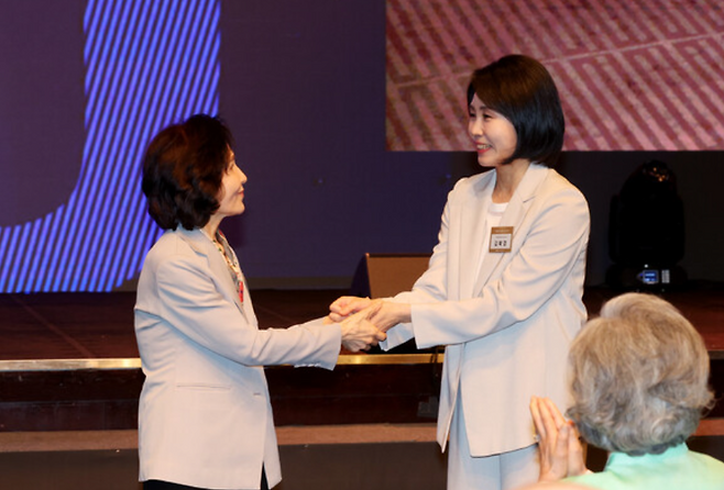 국민의힘 김문수 대선 후보의 부인 설난영 씨와 더불어민주당 이재명 대선 후보의 부인 김혜경 씨가 12일 서울 중구 신라호텔에서 열린 중앙신도회 창립 70주년 기념식에서 손을 맞잡고 있다. 연합뉴스