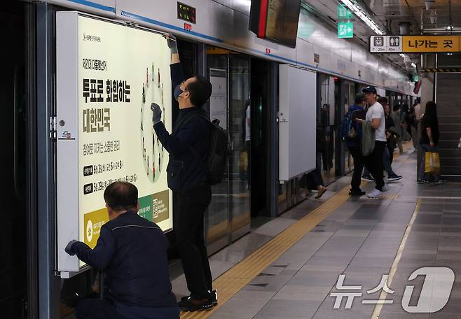 제21대 대통령선거를 20일 앞둔 14일 오전 서울 종로구 지하철 혜화역 승강장 스크린도어에 선관위 관계자들이 대선 홍보물 래핑작업을 하고 있다. 2025.5.14/뉴스1 ⓒ News1 박세연 기자