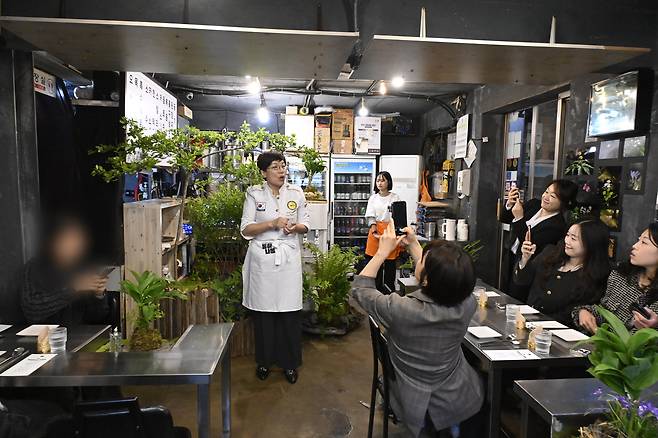 Participants in “Tonghanabom,” a unification-themed cultural program hosted by South Korea’s Ministry of Unification, listen to an introduction before tasting dishes prepared by North Korean defector chef Li Myong-ae at a restaurant in Mapo District, western Seoul, on May 9. [MINISTRY OF UNIFICATION]