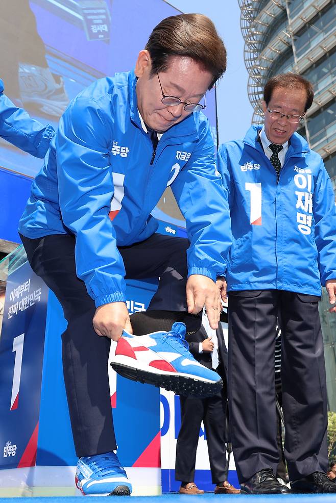 이재명 더불어민주당 대선 후보가 6·3 대통령선거 공식 선거운동 첫날인 지난 12일 서울 광화문 청계광장에서 열린 중앙선대위 출정식 및 첫 유세에서 구두를 벗고 운동화로 갈아신고 있다. [연합]