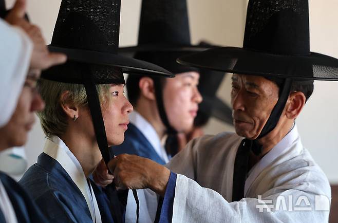[경산=뉴시스] 이무열 기자 = 성년의 날을 앞둔 14일 경북 경산시 영남대학교 민속촌 구계서원에서 열린 관례·계례 행사에서 외국인 유학생들이 갓을 쓰는 의식인 관례에 임하고 있다. 2025.05.14. lmy@newsis.com