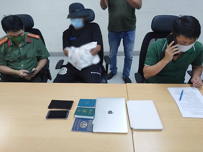[서울=뉴시스] 베트남 공안부가 경찰청과 3년간 국제공조를 통해 베트남에서 국내로 마약을 밀수입해 판매하던 A씨(가운데)를 지난 17일 베트남 호치민 현지에서 검거하고 마약 판매에 이용된 대포폰, 위조여권, 노트북을 압수하고 있다. (사진=뉴시스DB) photo@newsis.com *재판매 및 DB 금지