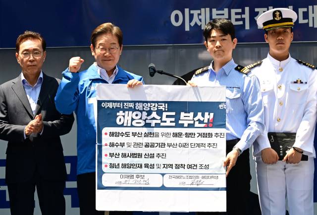 이재명 더불어민주당 대선 후보가 14일 부산 부산진구 서면거리에서 ‘해양수도부산 이전 공약서’에 서명한 뒤 기념 촬영을 하고 있다. 부산=오승현 기자