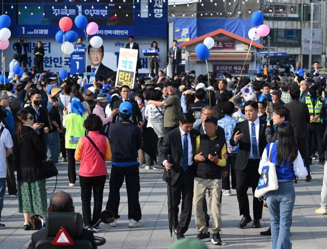 이재명 더불어민주당 대선 후보가 14일 경남 통영 강구안 문화마당에서 유권자들에게 지지를 호소하고 있는 가운데 이 후보에게 항의하던 한 시민이 경호원들에 의해 제지당하고 있다. 이 후보는 15일 영·호남 화합의 상징인 경남 하동군 화개장터를 시작으로 전남 광양·여수·순천·목포 등 호남지역을 방문해 유권자들과 만날 예정이다. 통영=오승현 기자 2025.05.14