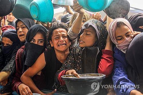 음식 얻으려는 가자지구 주민들 (가자지구 칸유니스 UPI=연합뉴스) 2025년 5월 12일 가자지구 칸유니스에서 팔레스타인인 주민들이 구호단체들이 나눠주는 음식을 받으려고 하고 있다. (Photo by Anas Deeb/UPI) 2025.5.14.