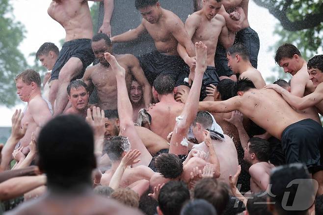 미국 해군사관학교에서 사관생도들이 14일(현지시간) 미국 메릴랜드 주 아나폴리스 미 해군 사관학교에서 '딕시 컵'을 떨어뜨리기 위해 인간 피라미드를 만들어 헌던 기념물 꼭대기에 오르고 있다. ⓒ AFP=뉴스1