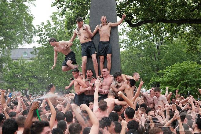 미국 해군사관학교에서 사관생도들이 14일(현지시간) 미국 메릴랜드 주 아나폴리스 미 해군 사관학교에서 '딕시 컵'을 떨어뜨리기 위해 인간 피라미드를 만들어 헌던 기념물 꼭대기에 오르고 있다. ⓒ AFP=뉴스1