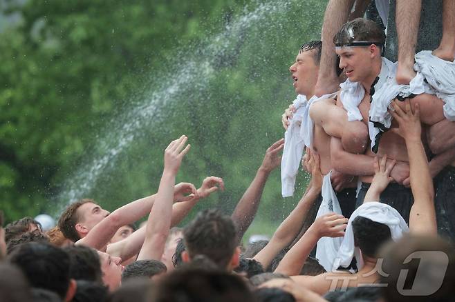 미국 해군사관학교에서 사관생도들이 14일(현지시간) 미국 메릴랜드 주 아나폴리스 미 해군 사관학교에서 '딕시 컵'을 떨어뜨리기 위해 인간 피라미드를 만들어 헌던 기념물 꼭대기에 오르고 있다. ⓒ AFP=뉴스1