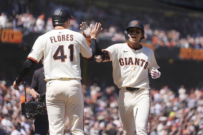 샌프란시스코 자이언츠 이정후가 15일(한국시각) 오라클파크에서 열린 애리조나 다이아몬드백스전에서 7회말 투런홈런을 터뜨리고 들어와 먼저 홈을 밟은 윌머 플로레스와 하이파이브를 하고 있다. AP연합뉴스