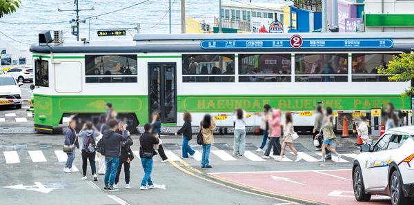 15일 부산 해운대구 청사포에서 해변열차와 바다를 배경으로 사진을 찍으려는 관광객이 도로 한복판까지 침범해 안전사고 우려가 나온다. 이원준 기자 windstorm@kookje.co.kr