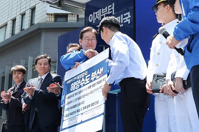 이재명 더불어민주당 대선 후보가 지난 14일 부산 부산진구 서면에서 권기흥 에이치라인해운해상직원노조 위원장과 해양수도 부산 협약서에 서명한 뒤 악수하고 있다. ⓒ연합뉴스