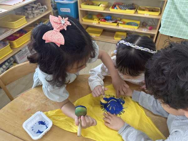 수원 매산유치원 유아들이 스텐실 기법을 활용해 청렴을 상징하는 푸른 손자국을 손수건에 찍는 활동을 하고 있다. /매산유치원 제공