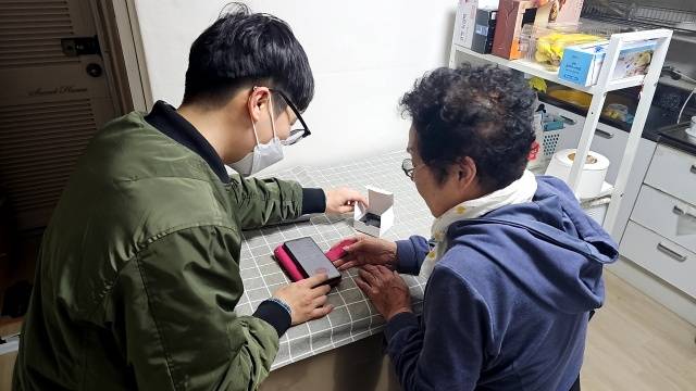 사회적 고립 가구를 방문해 모바일 앱 설치를 도와주는 모습. /마포구
