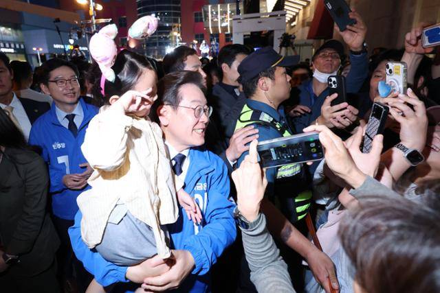 이재명 더불어민주당 대선 후보가 13일 울산 남구 롯데백화점 울산점 광장에서 열린 유세를 마친 뒤 아이를 껴안으며 기념촬영을 하고 있다. 뉴시스