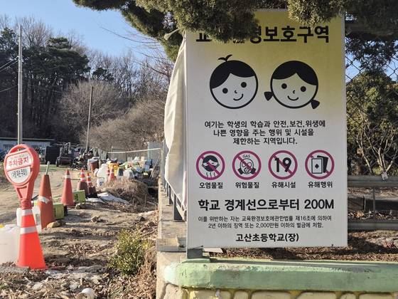 지난 14일 (구)고산초 교문 앞 ‘교육환경 보호구역: 학교 근처 오염물질, 유해시설 등을 제한한다’는 내용의 경고문이 있어있다. 하지만 교문으로부터 5m 떨어진 담장 옆엔 다 쓴 식용유통 30여개가 쌓인 채 방치 중이었다. 오소영 기자
