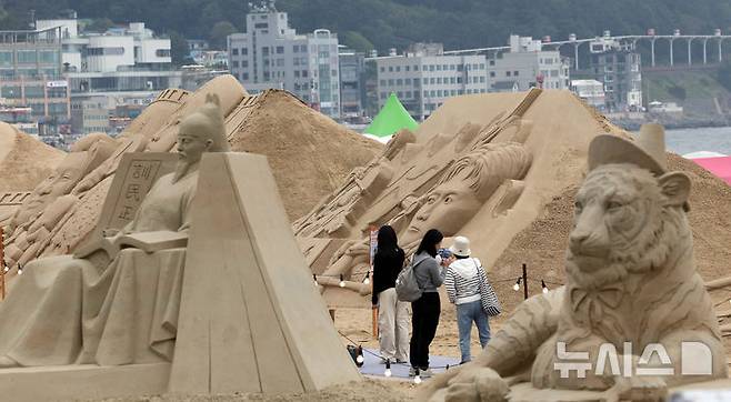 [부산=뉴시스] 하경민 기자 = 15일 부산 해운대구 해운대해수욕장을 찾은 시민과 관광객들이 다양한 모래조각 작품을 구경하고 있다. 해운대구는 오는 16~19일 '2025년 해운대 모래축제'를 개최한다. 올해 20주년을 맞은 모래축제는 '모래로 만나는 K-컬처'를 주제로 14명의 해외 모래 작가가 제작한 총 20여 개의 작품을 선보인다. 모래작품들은 축제 기간 이후인 오는 6월8일까지 전시될 예정이다. 2025.05.15. yulnetphoto@newsis.com