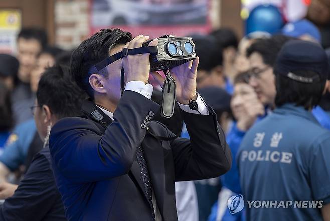 혹시 있을지 모를 위험에 대비해 (거제=연합뉴스) 황광모 기자 = 14일 경남 거제시에서 열린 더불어민주당 이재명 대선후보 유세에서 경호에 나선 경찰이 특수 쌍안경을 이용해 주변 건물의 움직임을 살피고 있다.  2025.5.14 hkmpooh@yna.co.kr