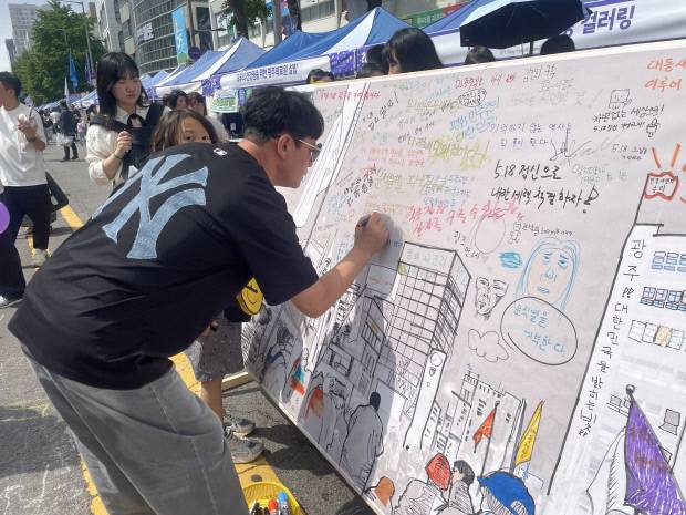 17일 광주시 동구 금남로에서 열린 5·18 전야제 시민난장 행사장에서 시민들이 5·18에 대한 글귀를 남기고 있다.