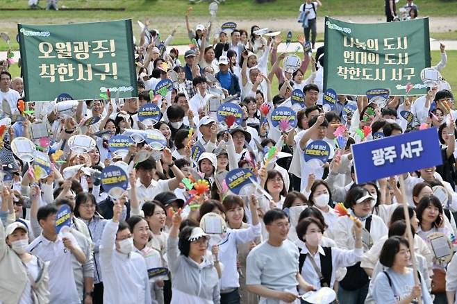 광주 서구청 공무원과 주민들이 ‘오월정신, 6월 3일 투표로 계승합시다’라는 문구가 적힌 현수막과 손팻말을 들고 있다. 서구 제공