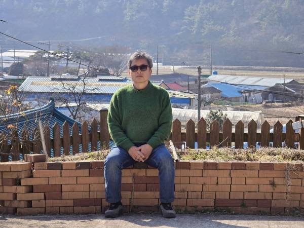 고성 자택 마당에 앉은 동길산 시인. 그는 "시인의 색깔이 있다면 이파리 다 떨어진 감나무 가지에 가깝다"고 말한다.