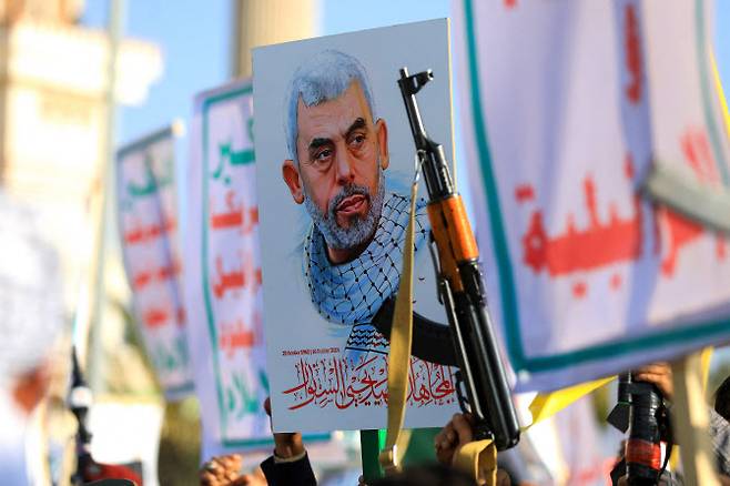 2024년 11월 29일 후티가 장악한 수도 사나에서 열린 가자 연대 집회에서 예멘인들이 소총을 휘두르며 살해된 하마스 지도자 야히야 신와르의 사진을 들고 있다. (사진=AFP)