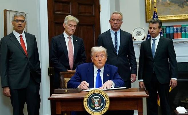 도널드 트럼프 미국 대통령이 지난 12일 미 워싱턴 DC 백악관 루스벨트룸에서 새로운 미·중 무역협정, 고가의 처방약 문제 등에 관해 발언한 뒤 처방약 가격인하 조치를 담은 행정명령에 서명하고 있다. 뒷줄 왼쪽부터 마틴 마카리 미국 식품의약국(FDA) 국장, 제이 바타차르야 국립보건원(NIH) 원장, 로버트 케네디 주니어 보건복지부 장관, 메흐메트 오즈 메디케어·메디케이드 서비스센터(CMMS) 국장. ⓒ EPA/연합뉴스